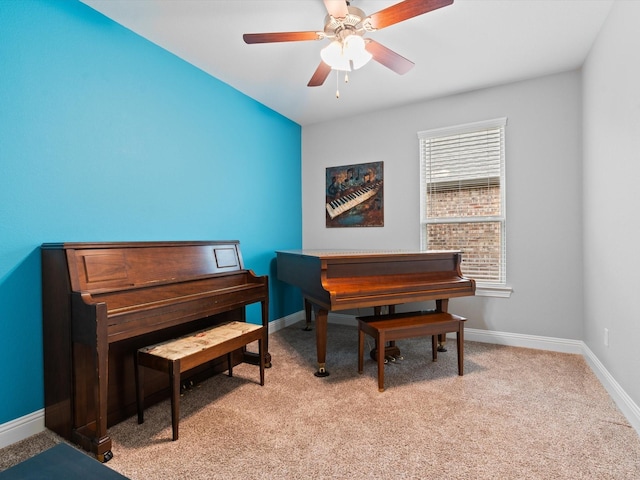 living area featuring light carpet, a ceiling fan, and baseboards