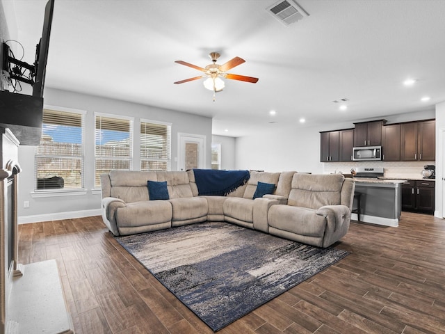 living area featuring a ceiling fan, baseboards, visible vents, and dark wood-style flooring