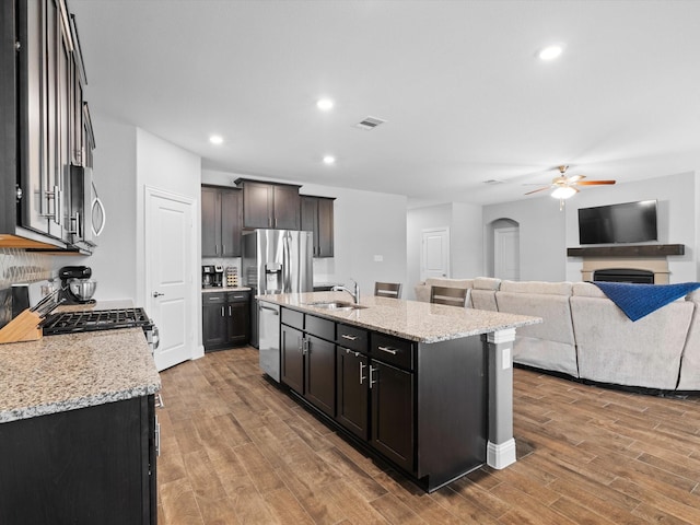 kitchen featuring stainless steel appliances, light wood-type flooring, a sink, and arched walkways