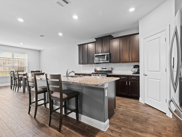 kitchen with wood finish floors, visible vents, decorative backsplash, appliances with stainless steel finishes, and a sink