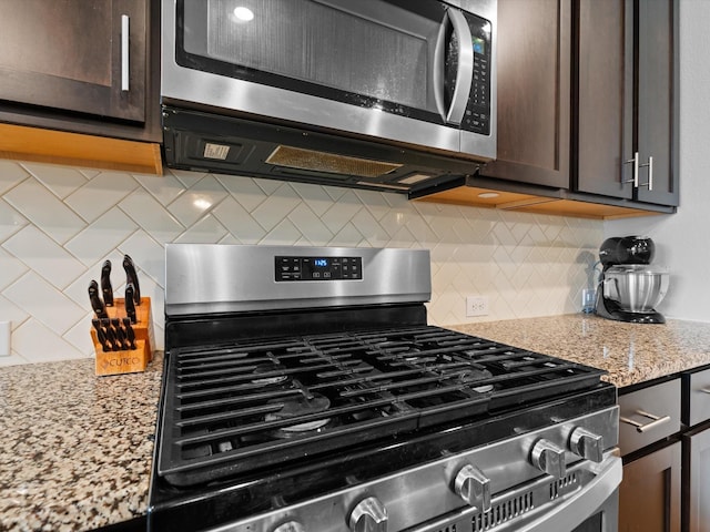 kitchen with stainless steel appliances, dark brown cabinets, light stone countertops, and tasteful backsplash