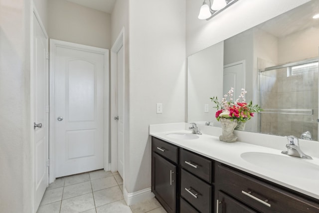 full bath with double vanity, tile patterned flooring, a shower stall, and a sink