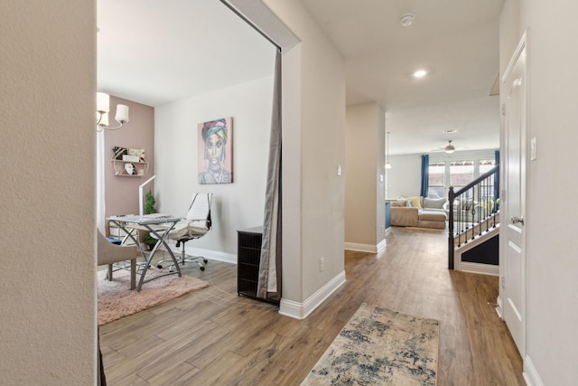 corridor with an inviting chandelier, stairs, baseboards, and wood finished floors