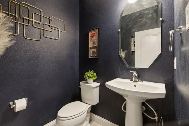 bathroom with baseboards, a textured wall, and toilet