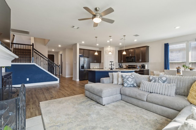 living area featuring visible vents, stairway, wood finished floors, and recessed lighting