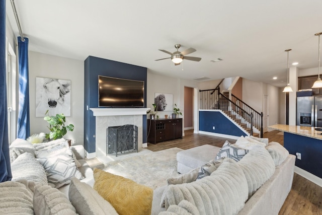 living area featuring wood finished floors, visible vents, baseboards, stairs, and a tiled fireplace