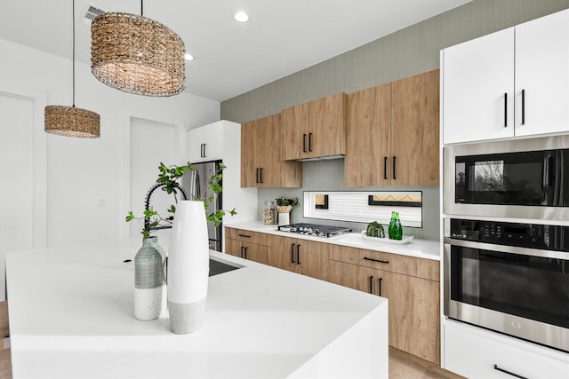 kitchen featuring an island with sink, backsplash, stainless steel appliances, and light countertops