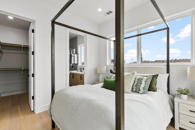 bedroom with recessed lighting, visible vents, light wood-style flooring, a spacious closet, and a sink