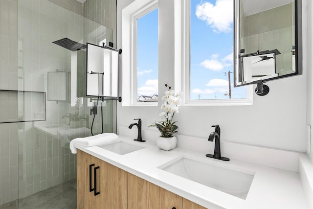 bathroom featuring a sink, a tile shower, and double vanity