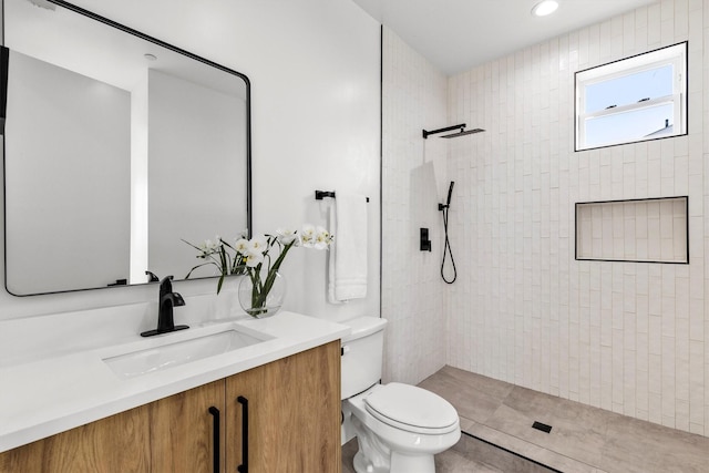 bathroom featuring toilet, tiled shower, and vanity