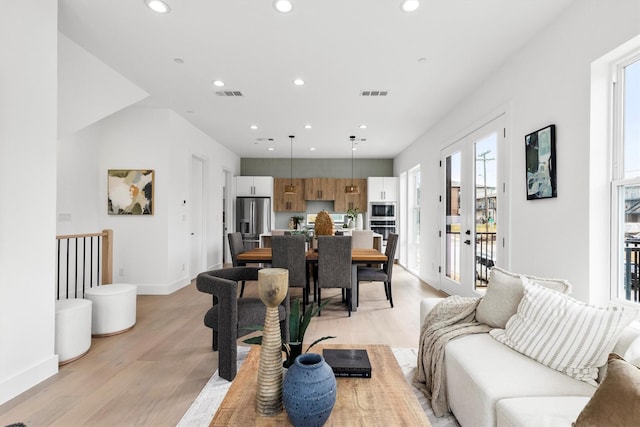 living room with baseboards, light wood-style flooring, visible vents, and recessed lighting