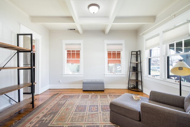 living area with visible vents, beamed ceiling, coffered ceiling, wood finished floors, and baseboards