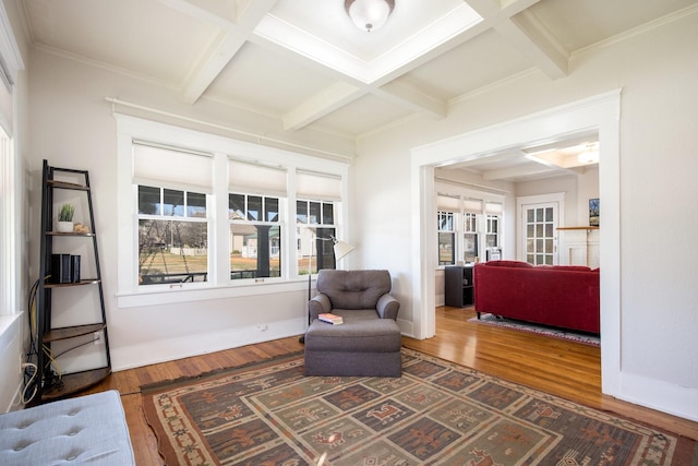 living area with coffered ceiling, baseboards, and wood finished floors