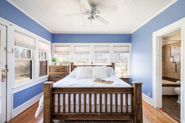 bedroom with multiple windows, wood finished floors, and baseboards