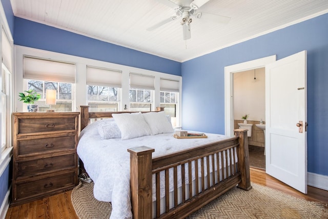 bedroom with multiple windows, ensuite bathroom, a ceiling fan, and wood finished floors