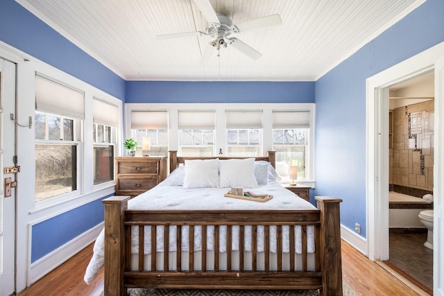 bedroom with multiple windows, baseboards, and wood finished floors