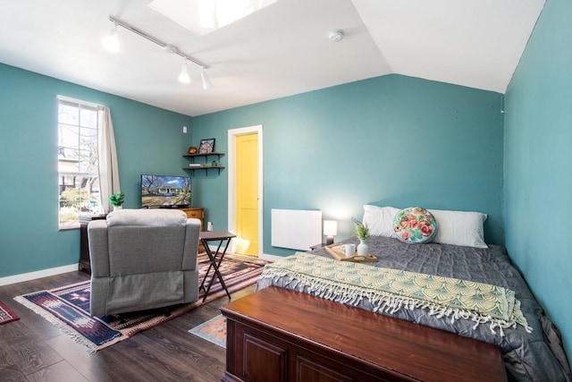 bedroom featuring rail lighting, baseboards, dark wood-style flooring, and vaulted ceiling