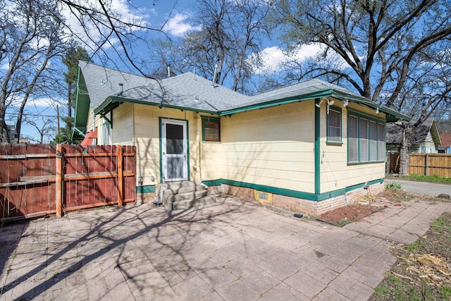 back of property with entry steps, fence, roof with shingles, crawl space, and a patio area