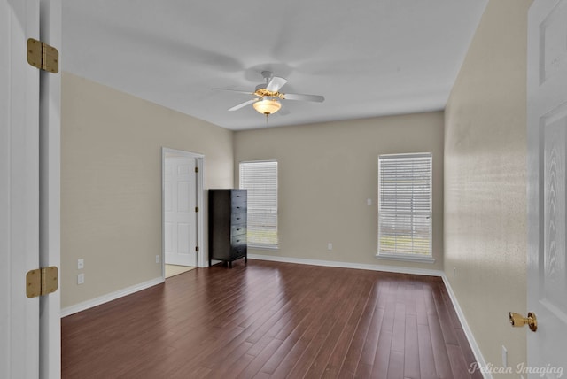 spare room with dark wood finished floors, baseboards, and ceiling fan