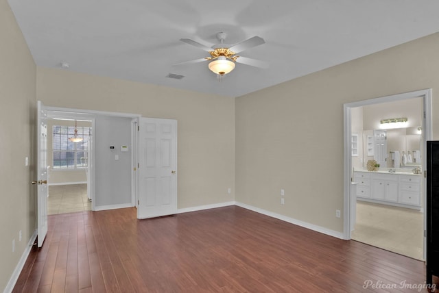 empty room with dark wood-style floors, visible vents, and baseboards