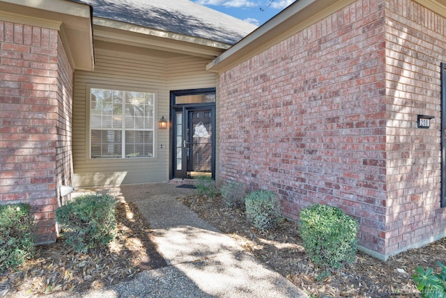 entrance to property with brick siding and roof with shingles