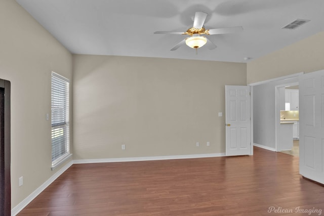 spare room featuring wood finished floors, visible vents, and baseboards