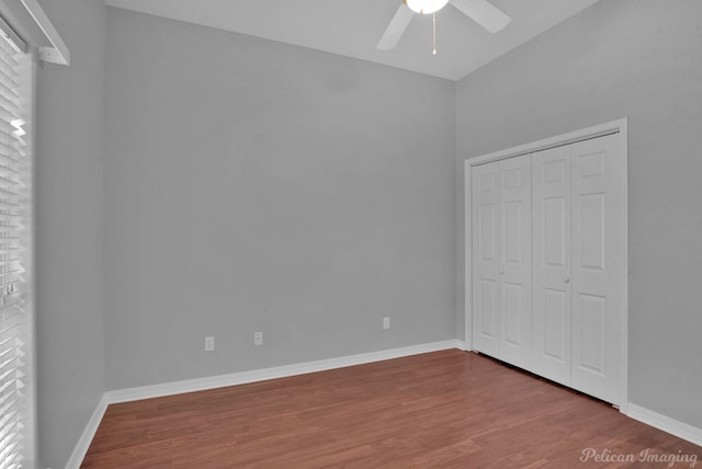 unfurnished bedroom with baseboards, multiple windows, wood finished floors, a closet, and a ceiling fan