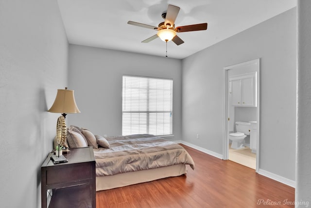 bedroom with a ceiling fan, wood finished floors, baseboards, and ensuite bathroom