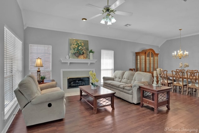 living room featuring visible vents, dark wood-type flooring, lofted ceiling, ceiling fan with notable chandelier, and a fireplace