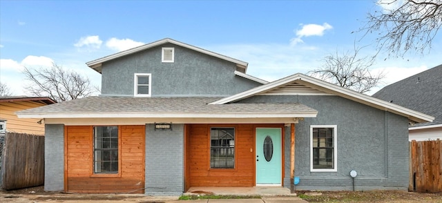 view of front of property with roof with shingles, fence, a porch, and stucco siding