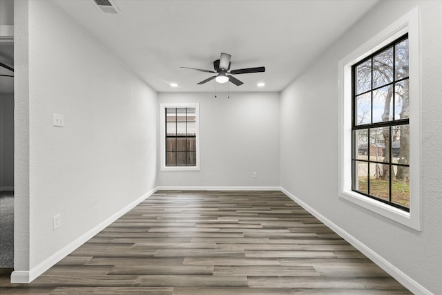 spare room featuring plenty of natural light, wood finished floors, visible vents, and baseboards