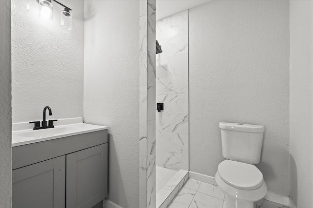 full bathroom with marble finish floor, a marble finish shower, toilet, vanity, and baseboards