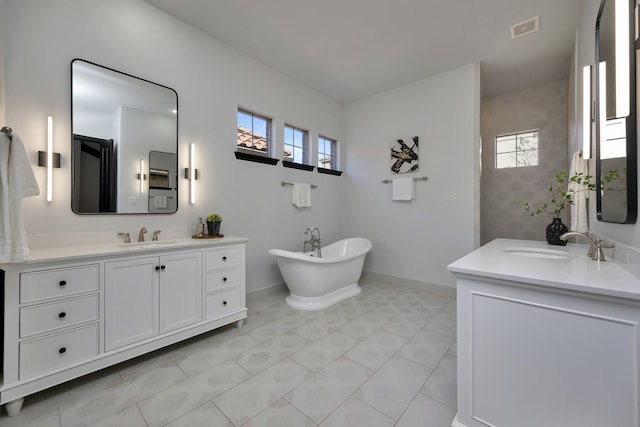 full bath with a soaking tub, two vanities, a sink, and visible vents