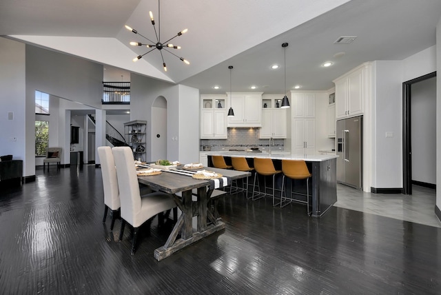 dining area with arched walkways, light wood finished floors, stairway, and an inviting chandelier