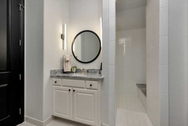 full bathroom featuring tiled shower and vanity