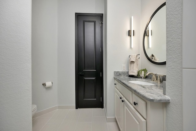 bathroom with toilet, vanity, baseboards, and tile patterned floors