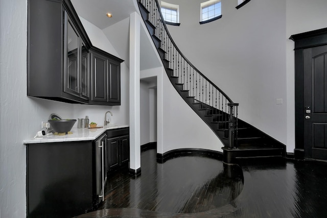 stairway with a high ceiling, wood finished floors, and baseboards