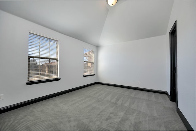 empty room with vaulted ceiling, baseboards, and light colored carpet