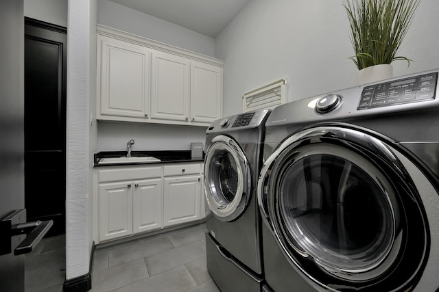 washroom with light tile patterned floors, separate washer and dryer, a sink, and cabinet space