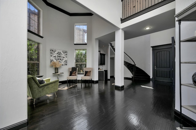 interior space with a towering ceiling, stairs, baseboards, and wood finished floors