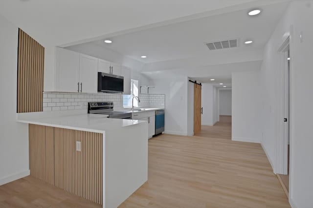 kitchen featuring a barn door, visible vents, light countertops, dishwasher, and stainless steel range with electric stovetop