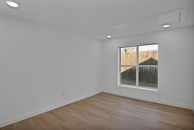 spare room featuring attic access, baseboards, wood finished floors, and recessed lighting