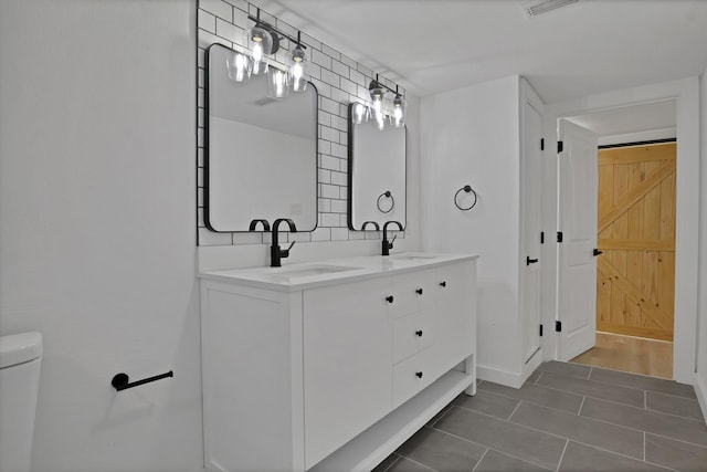 bathroom featuring double vanity, toilet, a sink, and tile patterned floors