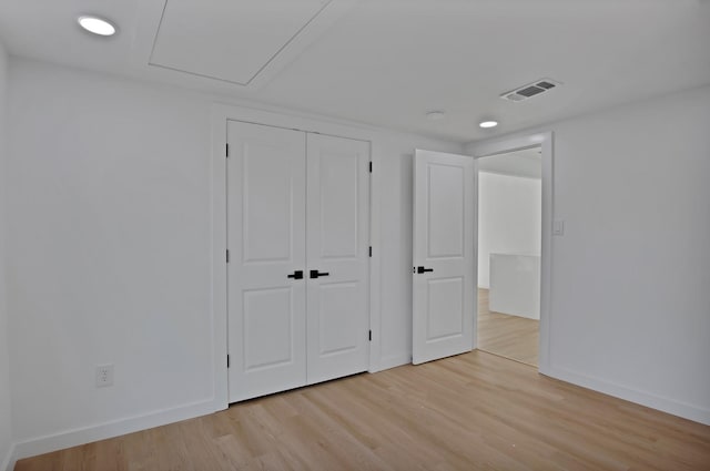 unfurnished bedroom featuring light wood-type flooring, baseboards, visible vents, and a closet