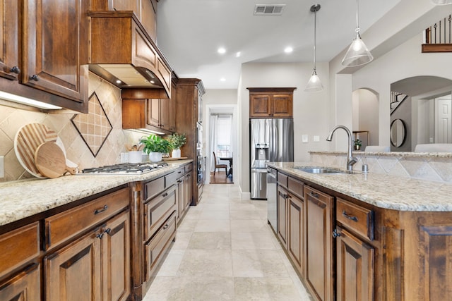 kitchen featuring stainless steel appliances, tasteful backsplash, visible vents, a sink, and light stone countertops