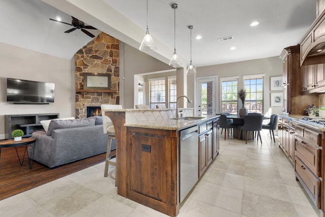 kitchen featuring a kitchen island with sink, stainless steel appliances, a fireplace, visible vents, and open floor plan