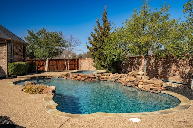 view of swimming pool with a fenced backyard and a pool with connected hot tub