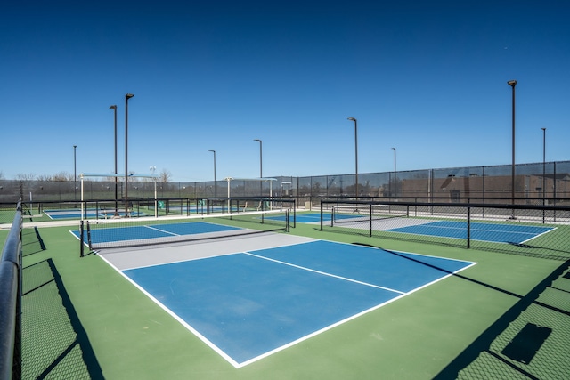 view of tennis court featuring community basketball court and fence