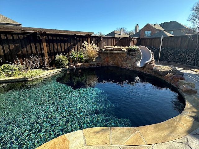 view of pool with a fenced in pool, a water slide, and a fenced backyard