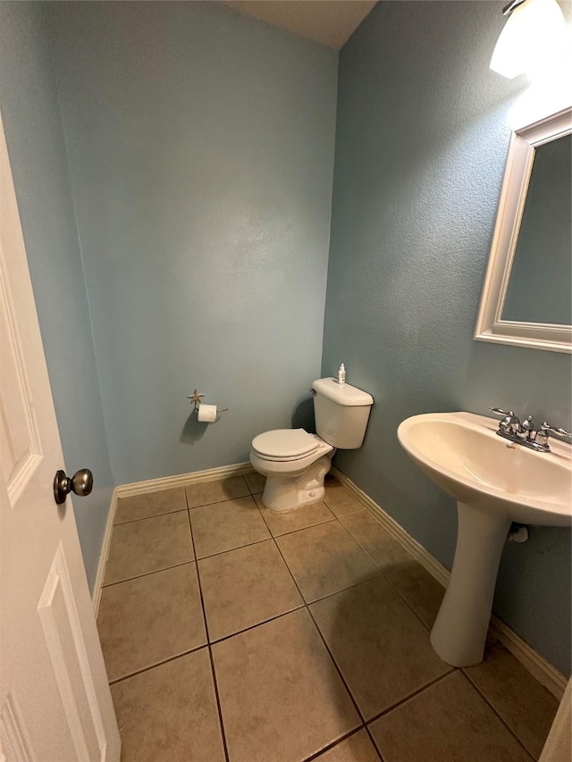 bathroom featuring tile patterned flooring, toilet, and baseboards